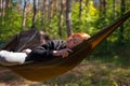 Woman relaxing in the hammock in the middle of a pine forest, watching sundown. Slow life concept. Hipster. Camping tent. Close-up
