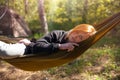 Woman relaxing in the hammock in the middle of a pine forest, watching sundown. Slow life concept. Hipster. Camping tent. Close-up