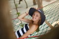 Woman relaxing in the hammock on tropical beach in the shadow, hot sunny day. Girl looks to camera with smile Royalty Free Stock Photo