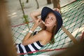 Woman relaxing in the hammock on tropical beach in the shadow, hot sunny day. Girl looks to camera with smile Royalty Free Stock Photo