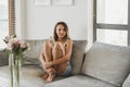 Female in beige crop top and denim shorts sitting at a sofa