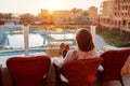 Woman relaxing at hotel balcony enjoying sunrise with swimming pool and sea view Royalty Free Stock Photo