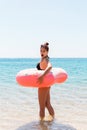 Woman relaxing with inflatable ring on the beach. shocked or surprised girl in the cold sea. Summer holidays and vacation concept Royalty Free Stock Photo