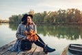 Woman relaxing on lake pier by boat admiring autumn landscape holding branches with leaves. Fall season activities Royalty Free Stock Photo