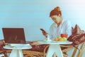 Woman relaxing listening music sitting on the sofa hands are holding mobile phone  and is working with a notebook Royalty Free Stock Photo