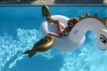 woman relaxing in luxury swimming pool resort hotel on big inflatable unicorn floating pegasus float Royalty Free Stock Photo