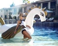 woman relaxing in luxury swimming pool resort hotel on big inflatable unicorn floating pegasus float Royalty Free Stock Photo