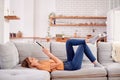 Woman Relaxing Lying On Sofa At Home Looking At Digital Tablet Royalty Free Stock Photo