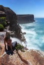 Woman watches waterfall flows off cliffs into ocean Royalty Free Stock Photo