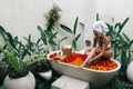 Woman relaxing in outdoor bath with flowers in Bali spa hotel Royalty Free Stock Photo