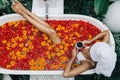 Woman relaxing in outdoor bath with flowers in Bali spa hotel Royalty Free Stock Photo