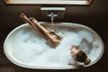 Woman relaxing in foam bath with bubbles in dark bathroom by window