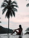 Woman relaxing by the pool in a luxurious beachfront hotel resort at sunset enjoying perfect beach holiday vacation. tropical beac