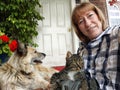 Woman Relaxing on Porch With Her Dog and Cat. A smiling woman enjoys time with her pet dog and cat on a homes porch Royalty Free Stock Photo