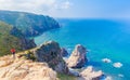 View of Woman relaxing on rocky cliff Cabo da Roca, Portugal