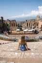 Rear view of woman looking at old ruin theater with blue sky in background