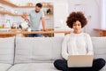 Woman Relaxing Sitting On Sofa At Home Using Laptop Computer With Man In Kitchen Pouring Drink Royalty Free Stock Photo