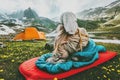 Woman relaxing in sleeping bag on red mat camping
