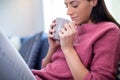 Young Woman Relaxing On Sofa At Home With Hot Drink Royalty Free Stock Photo