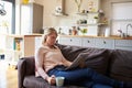 Woman Relaxing On Sofa Reading Newspaper In Modern Apartment Royalty Free Stock Photo