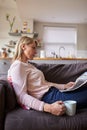 Woman Relaxing On Sofa Reading Newspaper In Modern Apartment Royalty Free Stock Photo