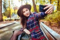 Woman relaxing in spring park. Girl taking selfie on smartphone sitting on bench outdoors Royalty Free Stock Photo