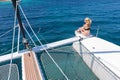 Woman relaxing on a summer sailing cruise, sitting on a luxury catamaran near picture perfect white sandy beach on Royalty Free Stock Photo