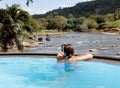 Woman relaxing in swimming pool and watching a Herd of Young elephants in river water hosing in Pinnawala Elephant Orphanage Royalty Free Stock Photo