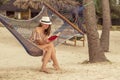 Woman sitting in a hammock on the beach reading a book Royalty Free Stock Photo