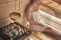 Woman relaxing in wellness spa, sweating in Finnish sauna, focus on sauna stove Royalty Free Stock Photo