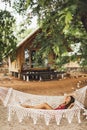 Woman relaxing in the white macrame hammock on tropical beach. Travel, leisure