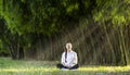 Woman relaxingly practicing meditation in the bamboo forest to attain happiness from inner peace wisdom for healthy wellness mind