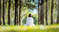 Woman relaxingly practicing meditation in the pine forest to attain happiness from inner peace wisdom with beam of sun light for