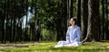 Woman relaxingly practicing meditation in the pine forest to attain happiness from inner peace wisdom with beam of sun light for