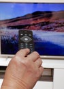 Woman with remote control in hand changing TV channels Royalty Free Stock Photo