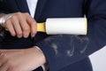 Woman removing cat hair from dark blue jacket with lint roller Royalty Free Stock Photo