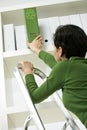 Woman removing green folder from shelf