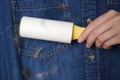 Woman removing hair from denim shirt with lint roller Royalty Free Stock Photo