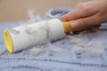 Woman removing hair from light blue knitted fabric with lint roller, closeup Royalty Free Stock Photo