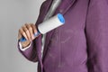 Woman removing hair from purple jacket with lint roller on light background Royalty Free Stock Photo