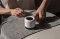 Woman removing lint from fabric with shaver. Handheld electric defuzzer. Cleaning from fuzz, fluff, dust, hair Royalty Free Stock Photo