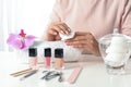 Woman removing polish from nails with cotton pad at table Royalty Free Stock Photo