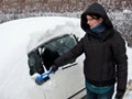 Woman removing snow from car