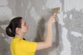 A woman repairman puts wallpaper glue on the wall. The wallpaper in the house and repair with their own hands yourself