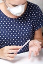 A woman with a respirator on her face gets a manicure. Removes old nail Polish with a nail buff