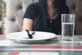 Woman in restaurant. Fork and a knife on empty white plate