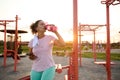 Woman resting and drinking water after running outdoor. Workout at hot summer sunset. Sport and healthy active lifestyle Royalty Free Stock Photo