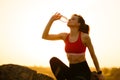 Woman Resting and Drinking Water after Running Outdoor. Workout at Hot Summer Sunset. Sport and Healthy Active Lifesyle.