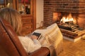 Woman resting in front of the fire in a fireplace in an armchair and covered with a blanket. Royalty Free Stock Photo