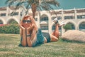 Young beauty woman in hat and sunglasses lying on grass on hotel garden on sunshine Royalty Free Stock Photo